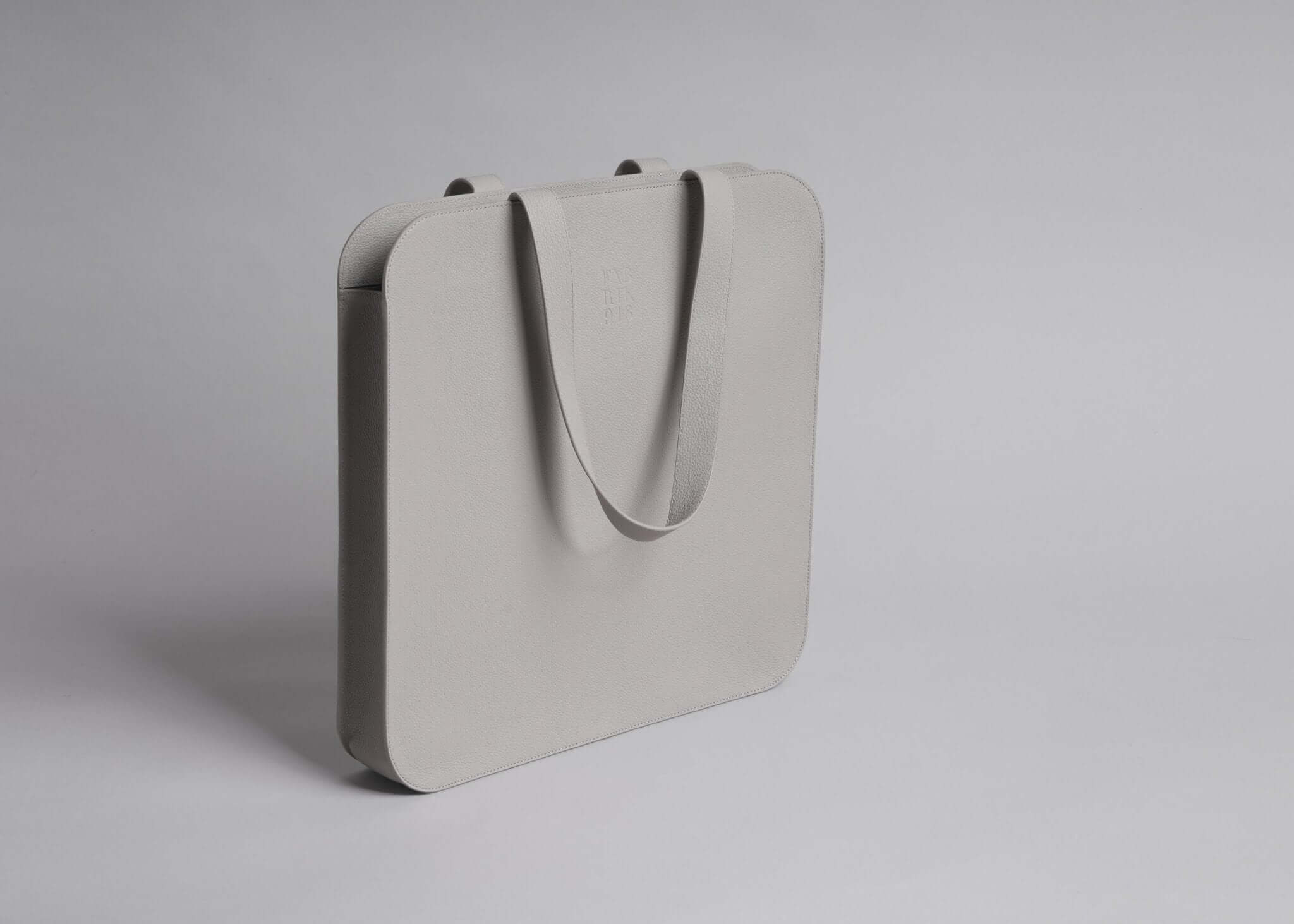 Minimalist gray leather tote bag with shoulder strap, perfect for 17-inch laptops.